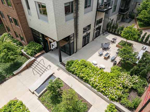 A courtyard surrounded by buildings with a bench and a table. at The MK, Indianapolis, Indiana