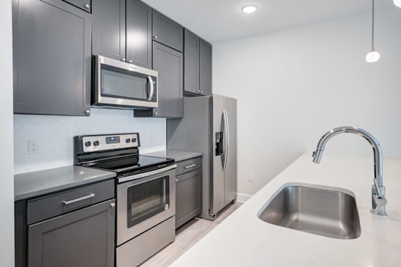 A modern kitchen with a stainless steel refrigerator, oven, and microwave. at The MK, Indianapolis