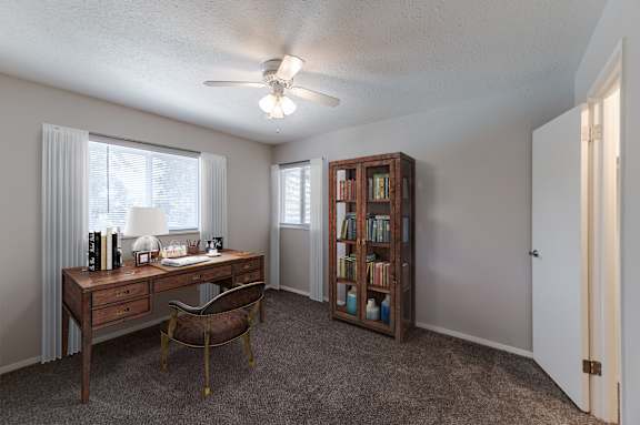 A room with a desk, chair, and bookshelf.