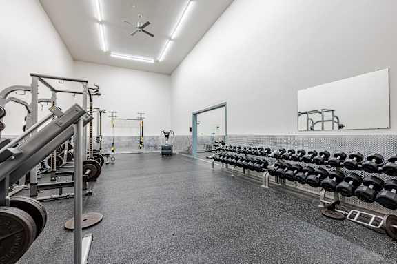 A gym with a mirror on the wall and weights on the floor.