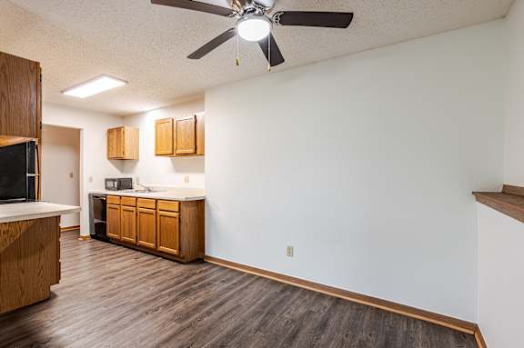 A kitchen with wooden cabinets and a ceiling fan.