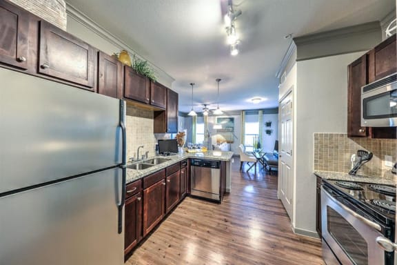a kitchen with stainless steel appliances and wooden cabinets at Waterstone at Cinco Ranch, Katy, TX