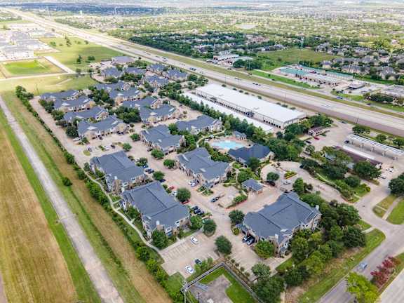 A bird's eye view of a residential area with houses and a highway at Waterstone at Cinco Ranch Apartments, Katy, TX 77450