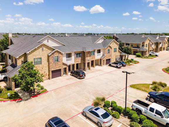 A suburban neighborhood with houses and cars parked in driveways at Waterstone at Cinco Ranch Apartments, Katy