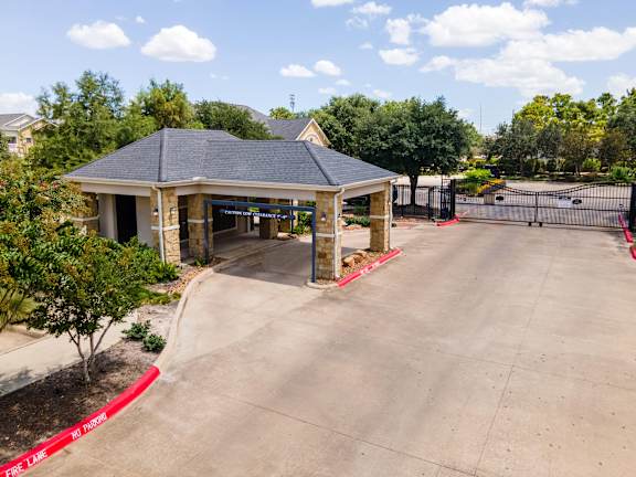 A gazebo-style building with a black roof is surrounded by a red curb and a black fence at Waterstone at Cinco Ranch Apartments, Katy Texas