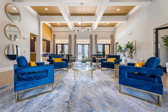 A living room with blue velvet chairs and a patterned rug at Waterstone at Cinco Ranch Apartments, Katy, 77450
