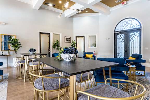 A dining room with a black table surrounded by blue chairs at Waterstone at Cinco Ranch Apartments, Katy Texas