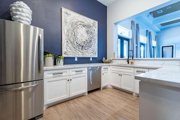 A modern kitchen with a stainless steel refrigerator and white cabinets at Waterstone at Cinco Ranch Apartments, Texas, 77450