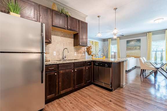 A modern kitchen with wooden cabinets and a stainless steel refrigerator at Waterstone at Cinco Ranch Apartments, Katy, 77450