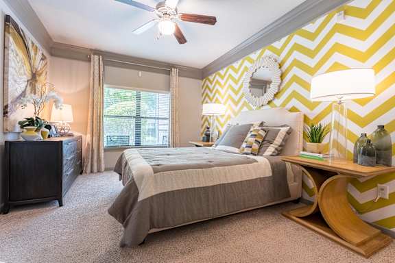 A bedroom with a bed, nightstand, and a ceiling fan at Waterstone at Cinco Ranch Apartments, Texas