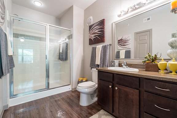 A bathroom with a toilet, sink, and shower at Waterstone at Cinco Ranch Apartments, Texas