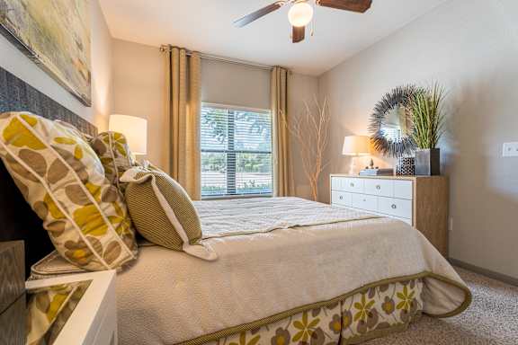 A bedroom with a bed, nightstand, and window at Waterstone at Cinco Ranch Apartments, Katy, TX