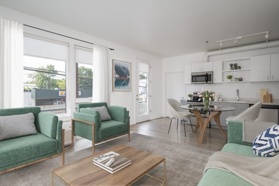 a living room with green couches and chairs and a dining room with a table