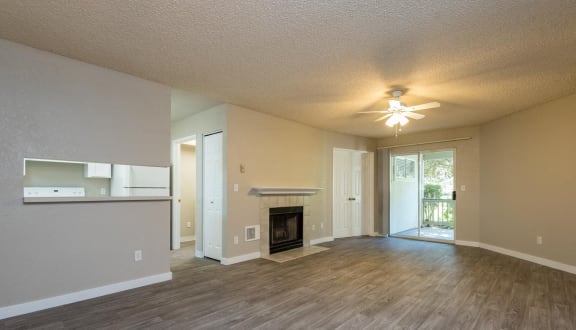 an empty living room with a fireplace and a ceiling fan