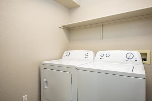 a washer and dryer in a room with a shelf above them