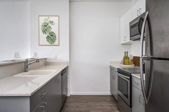 an empty kitchen with stainless steel appliances and white countertops