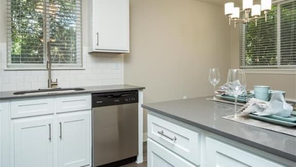 a kitchen with white cabinets and a sink and a dishwasher
