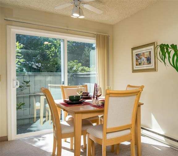 A dining room with a table set for two and a potted plant.