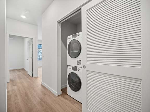 a white laundry room with a washer and dryer on the wall
