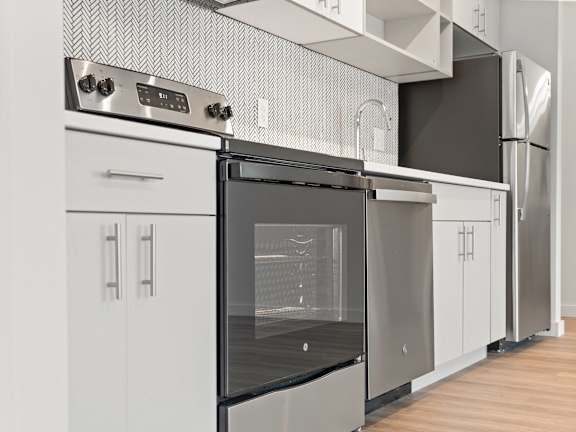 a kitchen with white cabinets and a stainless steel stove and dishwasher