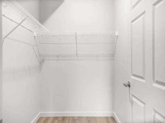 an empty closet in a home with white walls and a white closet door