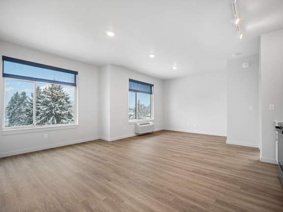 an empty living room with wood floors and a large window