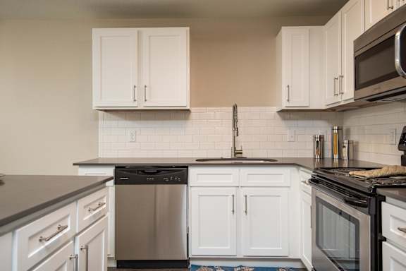 A kitchen with white cabinets and a black countertop.