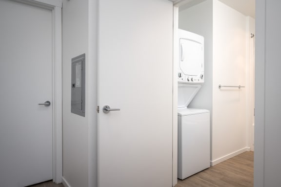 a white bathroom with a washing machine and a white door