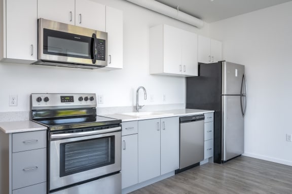 an empty kitchen with stainless steel appliances and white cabinets