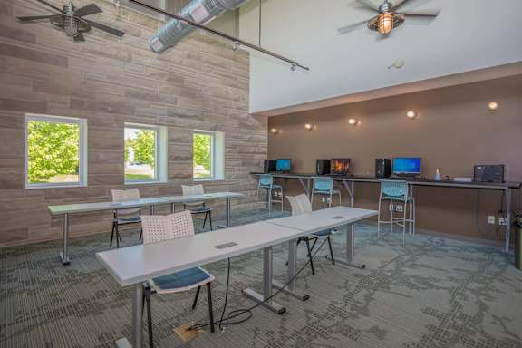 A room with tables and chairs and a ceiling fan.