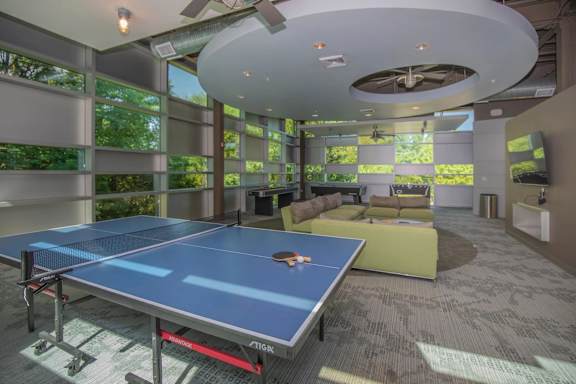 A ping pong table is in the middle of a room with a ceiling fan.