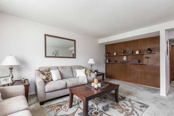 A living room with a grey couch, a wooden coffee table, and a mirror on the wall.