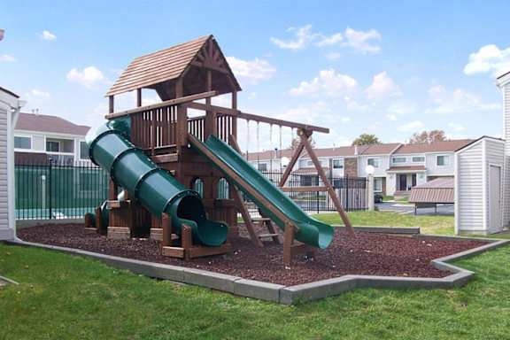 A playground with a green slide and a wooden structure.
