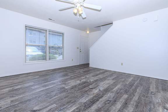 A room with a ceiling fan and a window overlooking a street.
