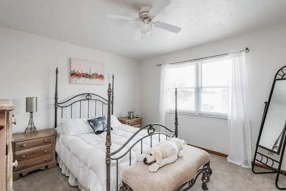 A bedroom with a four poster bed and a painting on the wall.