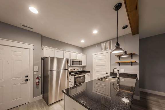 A modern kitchen with a granite countertop and stainless steel appliances.