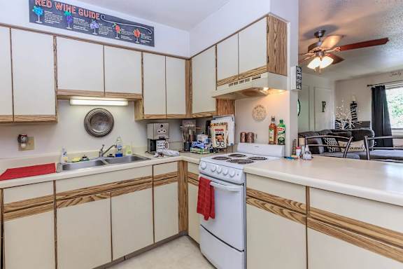 A kitchen with a white stove top oven and wooden cabinets.