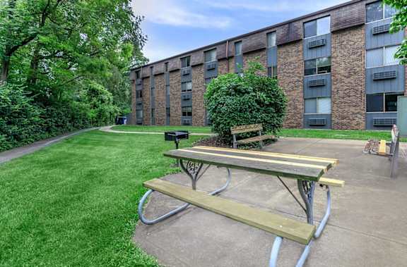 A picnic table sits in front of a brick building.