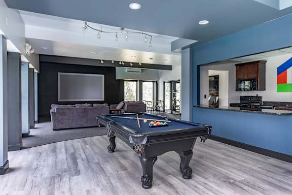 A pool table is in the middle of a room with a couch and a television.