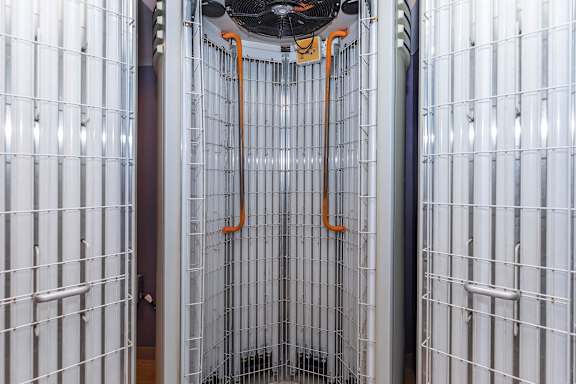 A wall of white panels with orange pipes hanging from the ceiling.