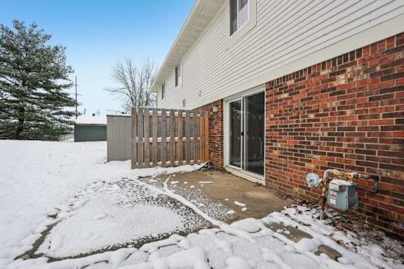 A house with a snow-covered ground and a brick wall.