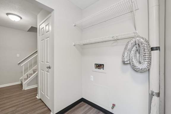 A white door is on the left side of a room with a white wall and a white shelf.
