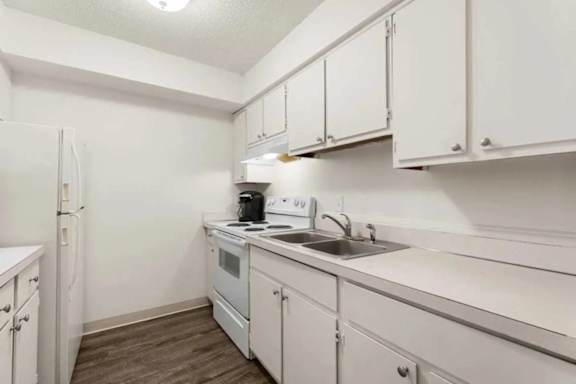 A kitchen with white cabinets and appliances.