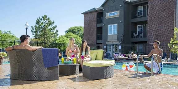 People relaxing in outdoor hot tubs in front of a multi-story building.