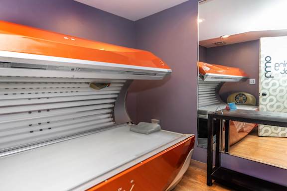 A bed with orange headboard and footboard in a room.