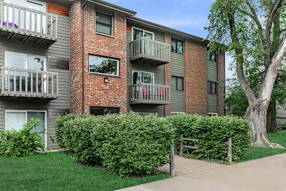 Apartment building with balconies and a tree in front.