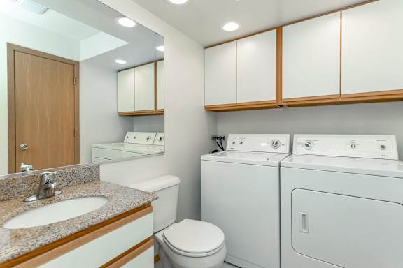 A bathroom with a sink, toilet, and washing machine.