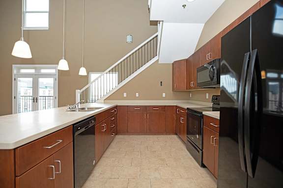 A kitchen with a black refrigerator and wooden cabinets.