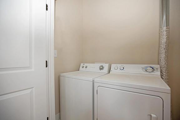Two white washing machines in a small laundry room.