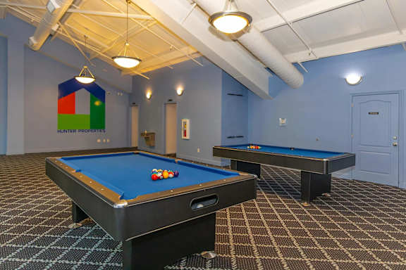 A pool table and a billiard table are in a room with a blue wall.